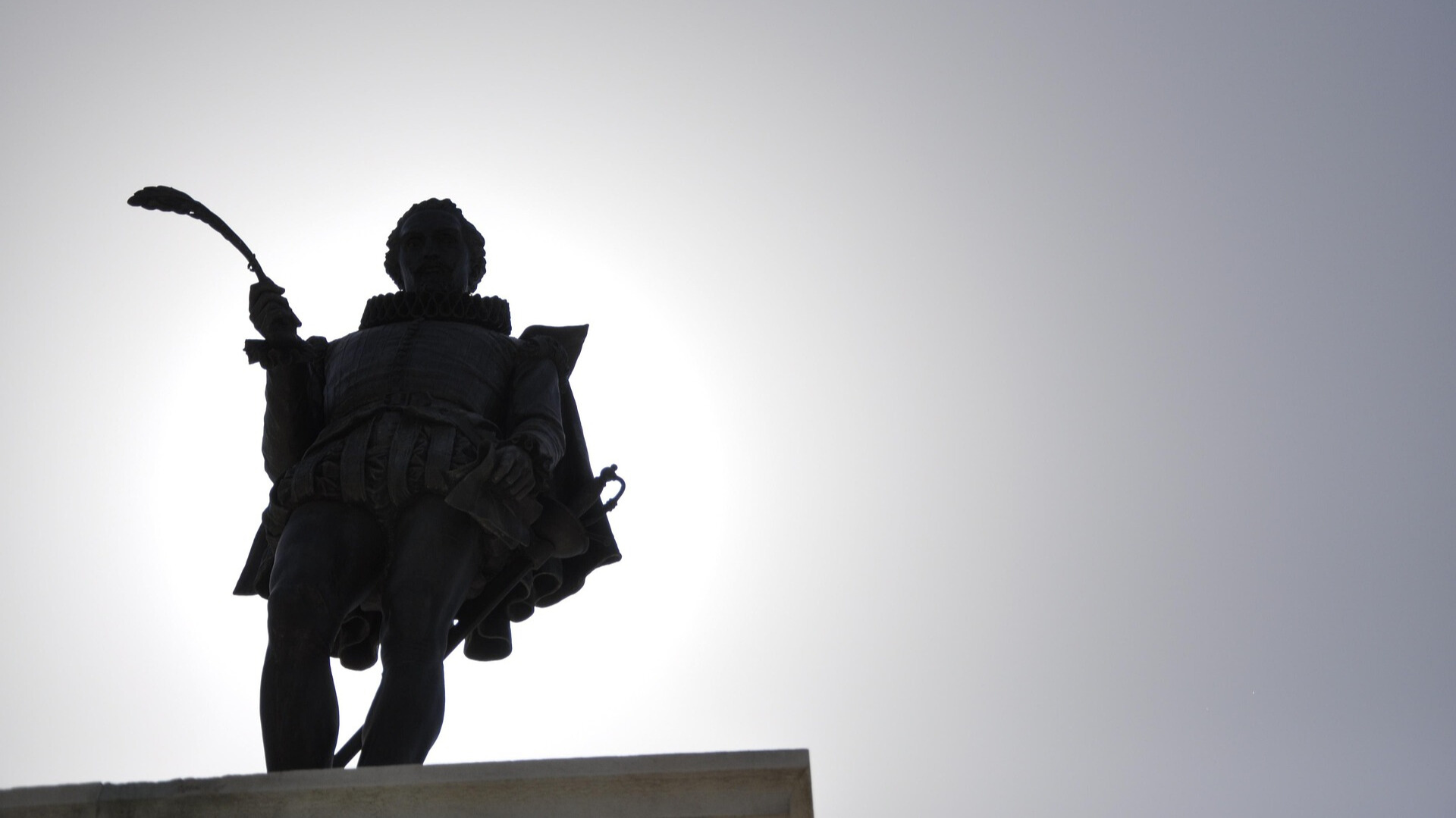 imagen de la estatua de Cervantes con cielo de fondo, tomada desde abajo.